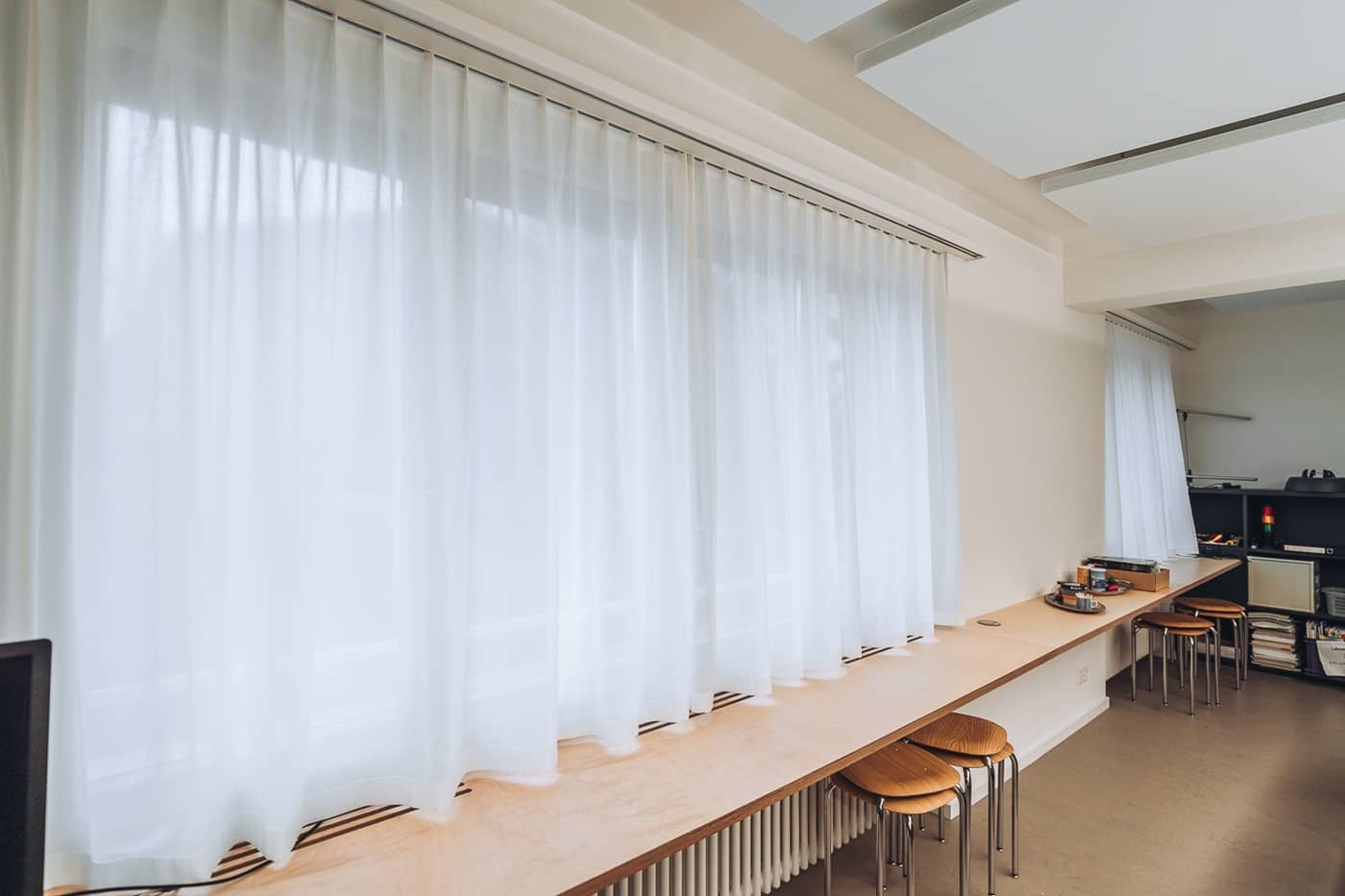 An einer langen Fensterfront h&auml;ngen schlichte, sch&ouml;ne Tagesvorh&auml;nge